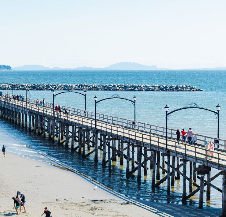 Wooden Pier at low tide with blue skies, people walking