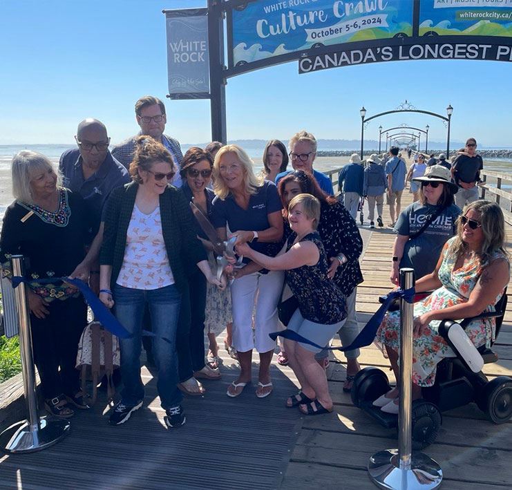 Group of people at ribbon cutting on wooden pier