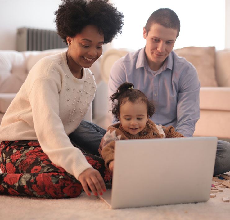 Mother, Father and Child sitting on floor with laptop