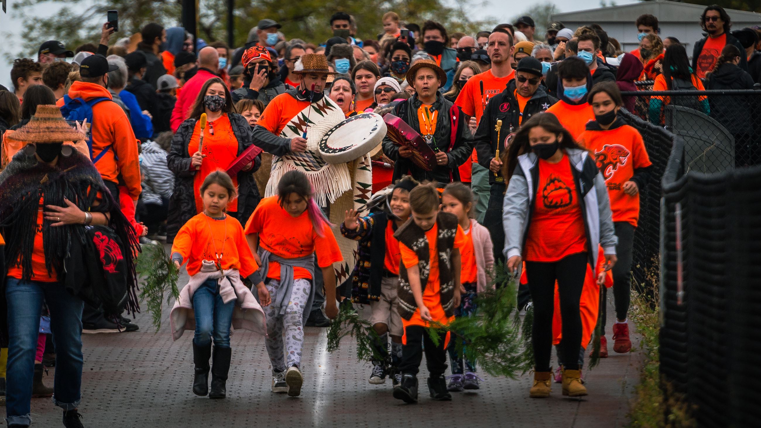 People walking together, wearing orange, led by members of Semiahmoo First Nation