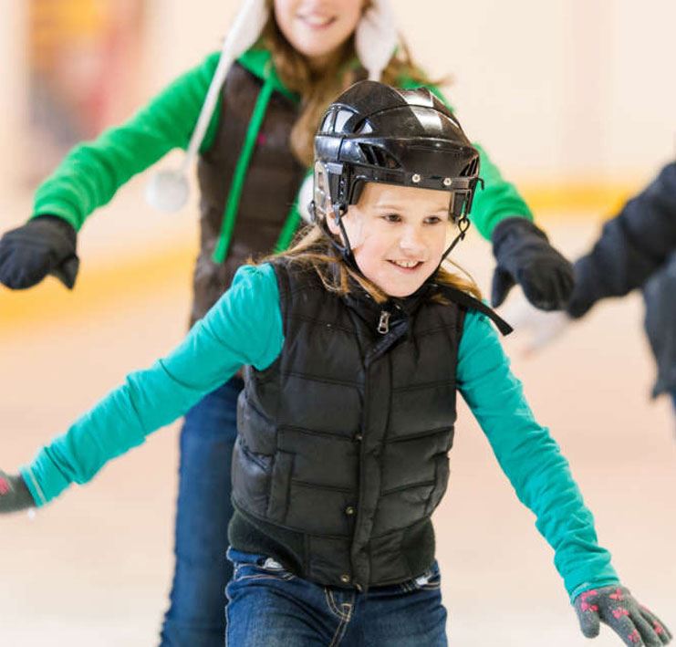 girl wearing helmet ice skating