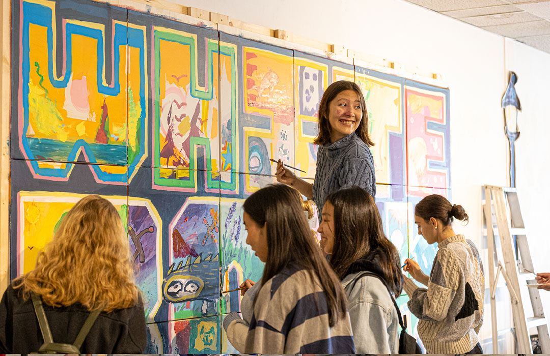 people painting artwork on a wall 