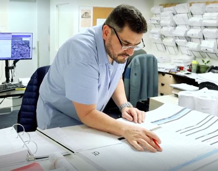 person wearing glasses looking at plans