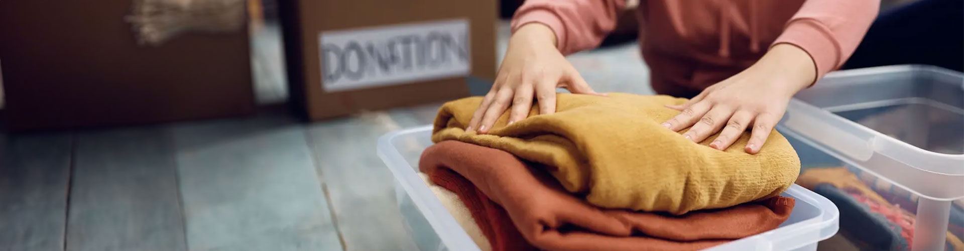person putting clothing into box for donation